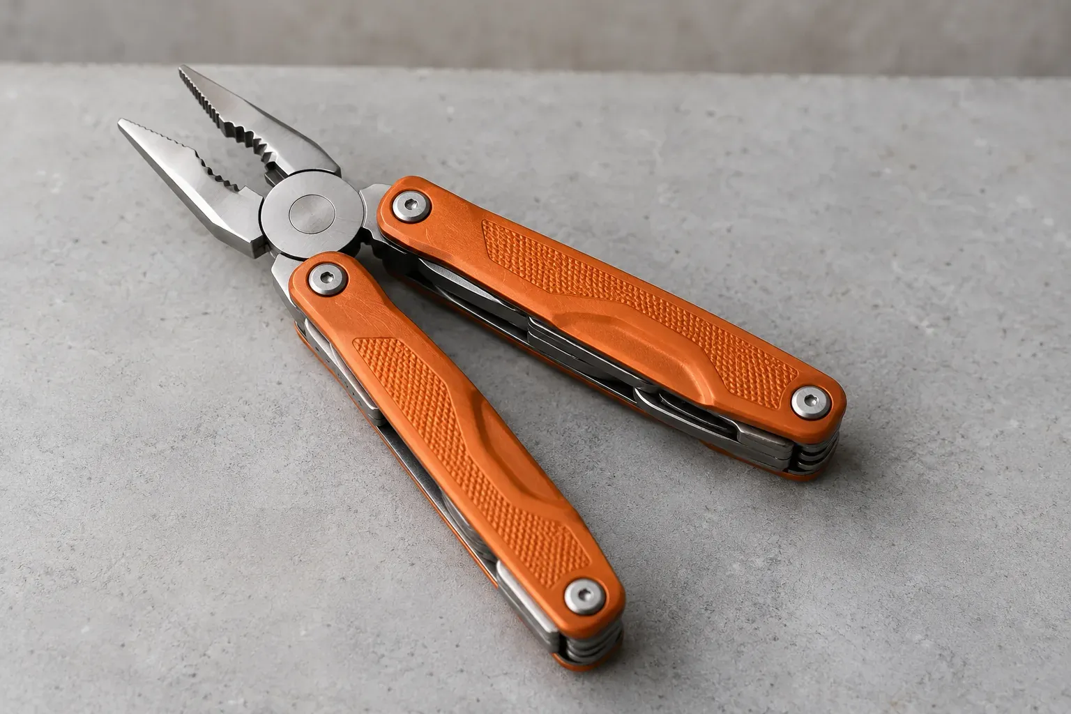 An orange-handled folding multitool, open as pliers, rests on a light grey workbench.