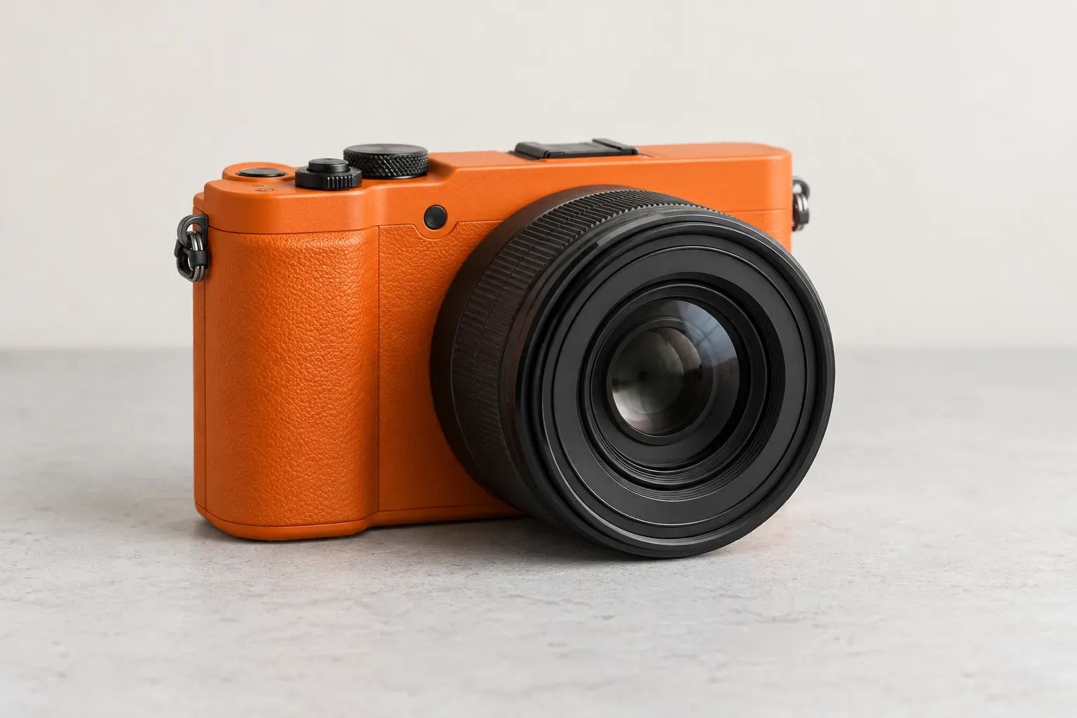 An orange camera with a charcoal lens on a pale grey surface.