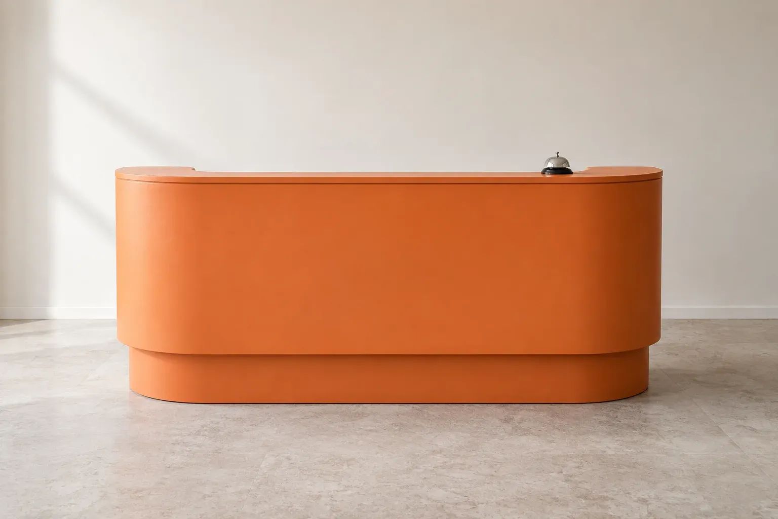 An orange reception desk with a small silver service bell in a calm office.