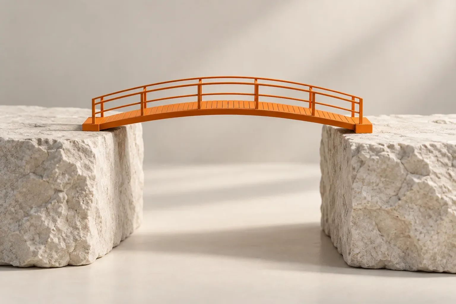 An orange bridge spanning a narrow gap between two neutral stone blocks.