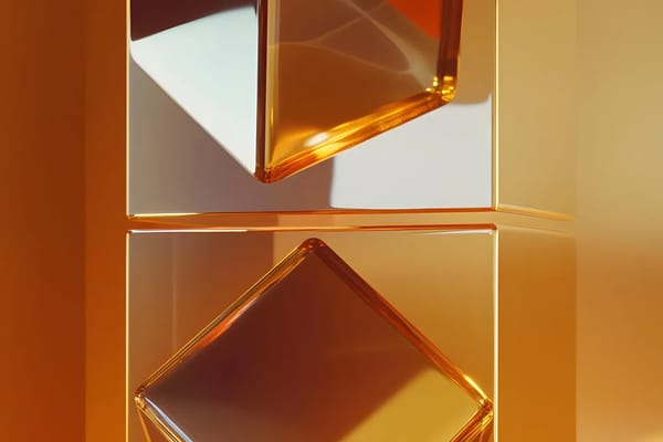 Two amber glass prisms meeting point to point between pale sculpted blocks