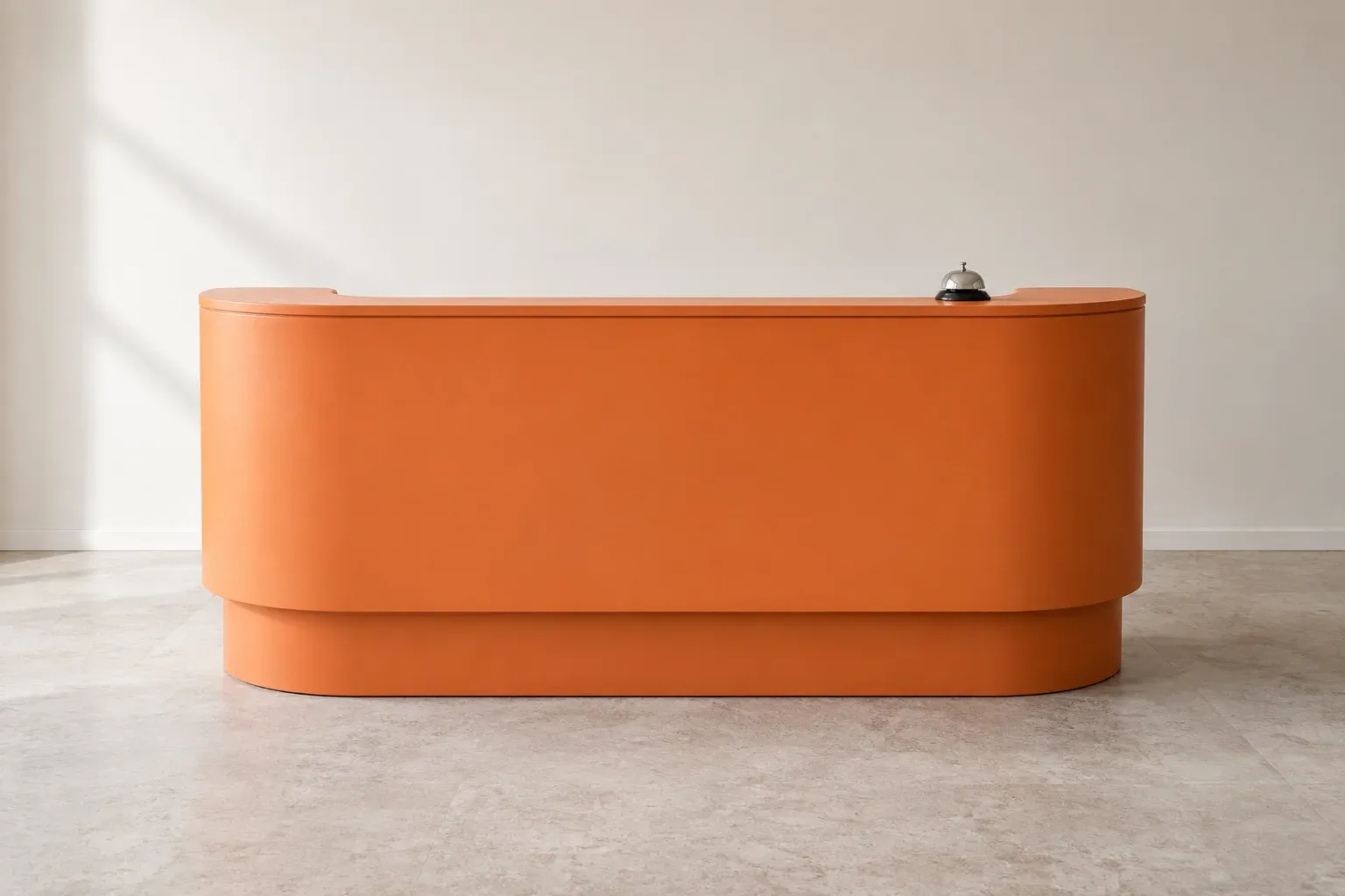 An orange reception desk with a small silver service bell in a calm office.