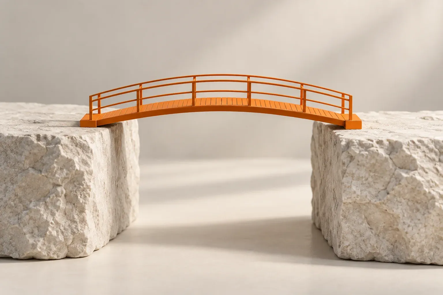 An orange bridge spanning a narrow gap between two neutral stone blocks.